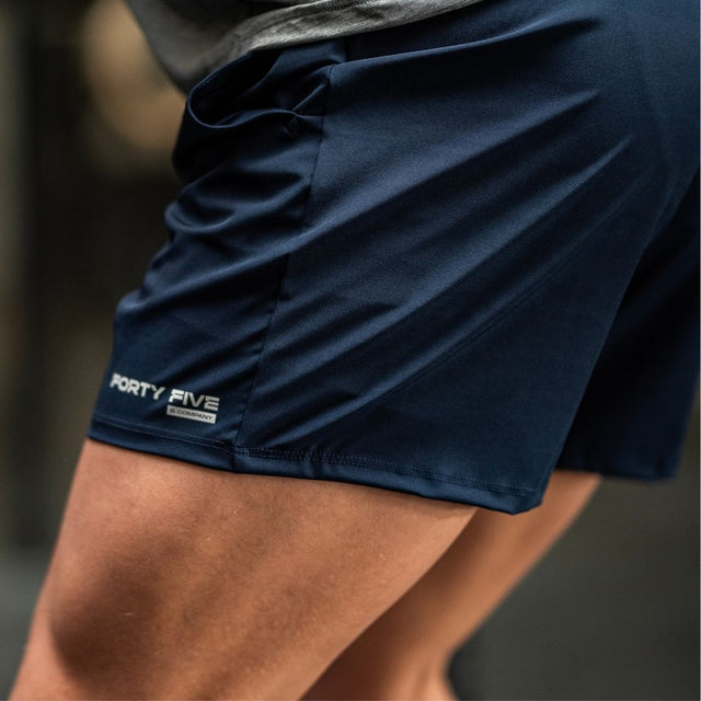 Navy athletic shorts with a brand logo on a blurred background