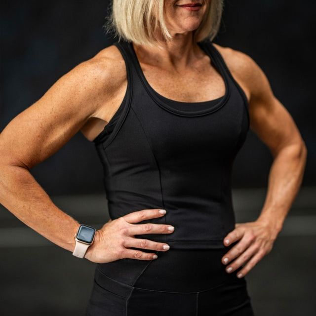 Person wearing a black tank top with a dark background