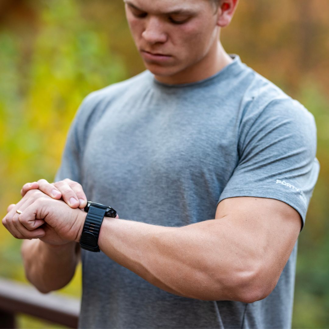 Man wearing a gray t-shirt and black watch outdoors