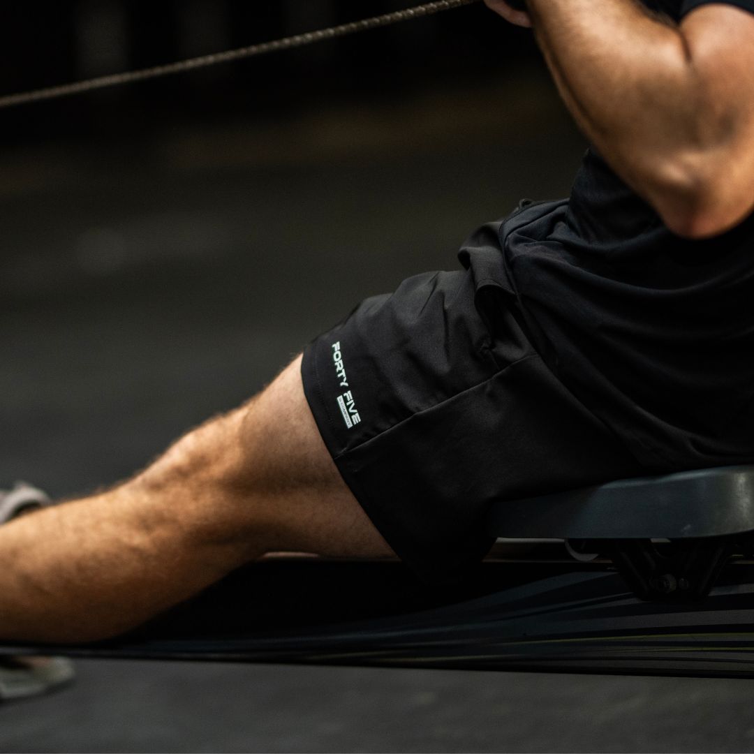 Person exercising on a machine with a focus on their shorts displaying a brand logo.
