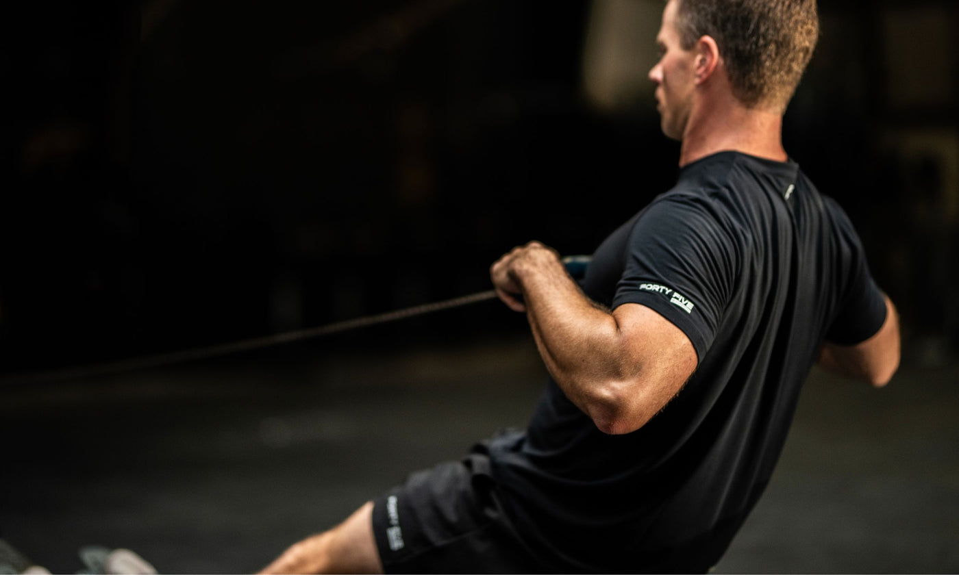 Man in a black t-shirt exercising with resistance bands in a dark setting