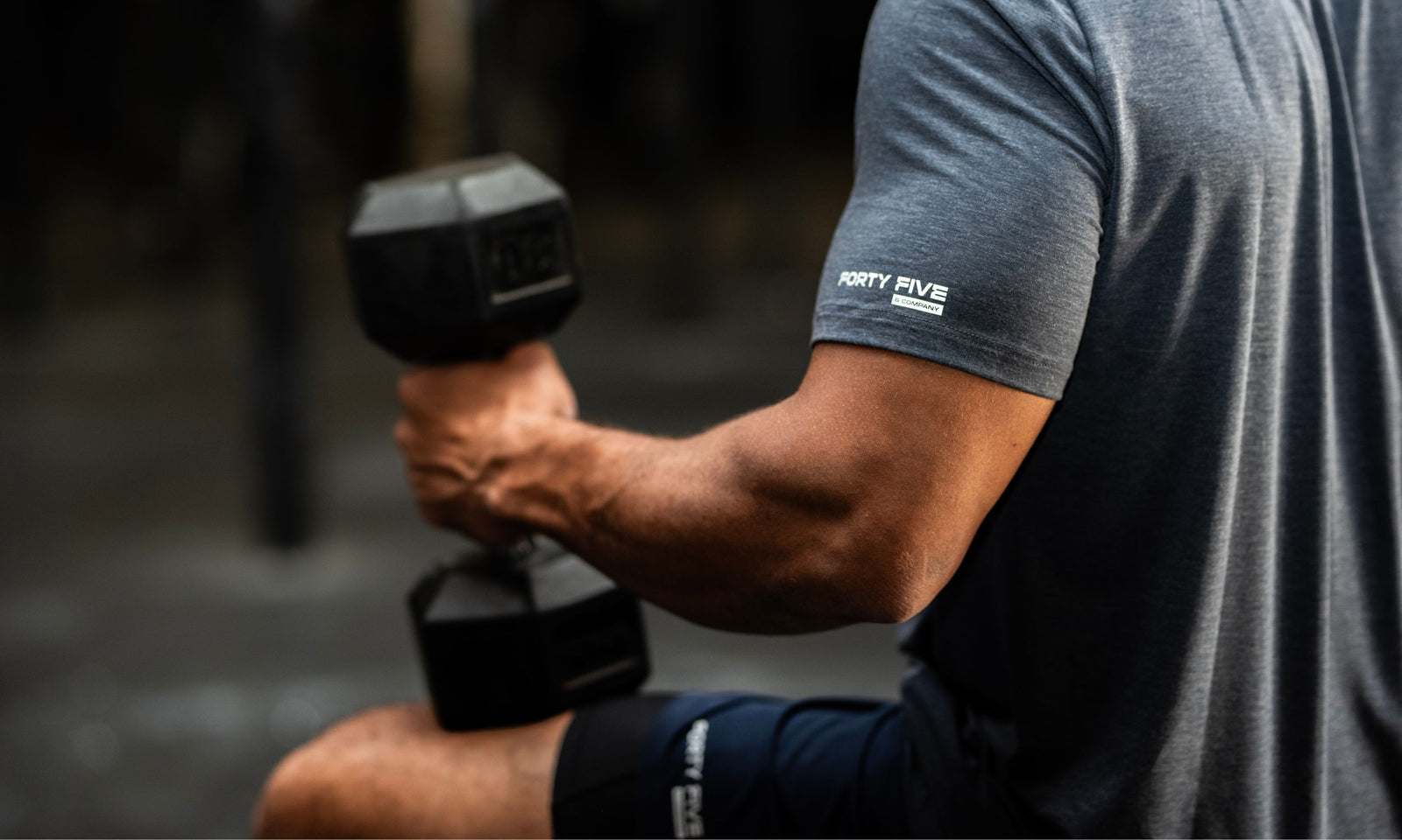 Person holding a dumbbell with a branded sleeve on a blurred background