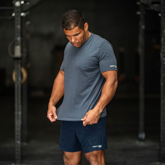 Man wearing a blue t-shirt and navy shorts in a gym setting
