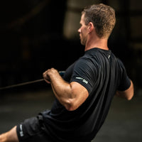 Man in a black t-shirt performing an exercise with a blurred background