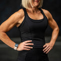 Person wearing a black tank top with a dark background