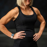 Person wearing a black tank top with a dark background
