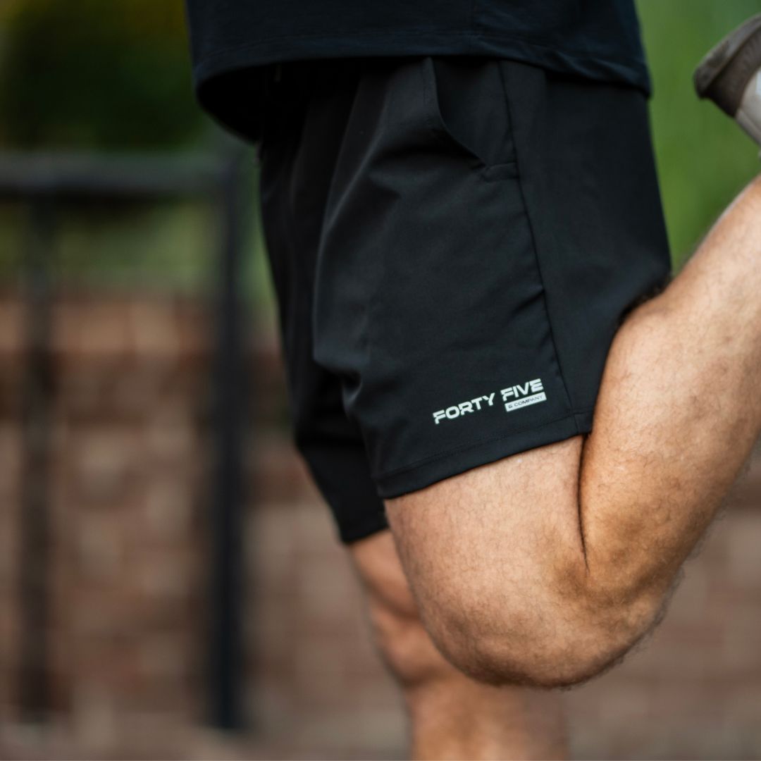Person wearing black shorts with 'Forty Five' logo, blurred background