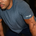 Man wearing a blue t-shirt with a brand logo on the sleeve.